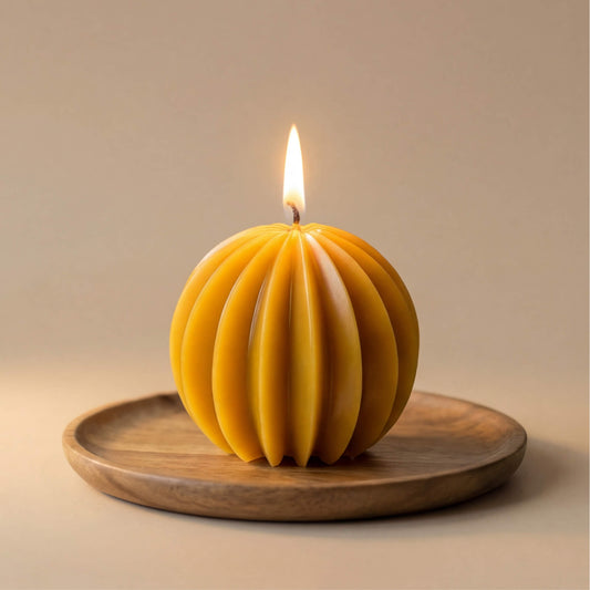 Natūrali geltona rutulio formos žvakė su giliomis vertikaliomis briaunomis