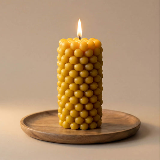 Natūralaus geltono vaško žvakė, sudaryta iš smulkių burbuliukų, cilindro formos