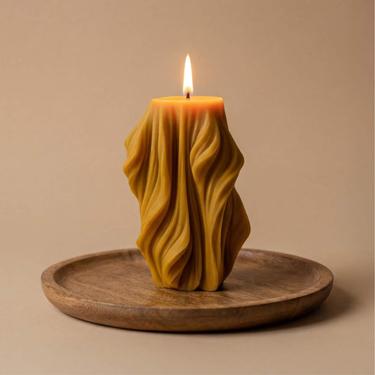 Natūralaus geltono vaško žvakė su giliomis banguotomis klostėmis, primenančiomis liepsną